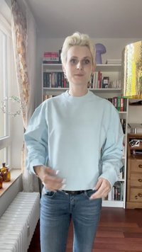 Sweatshirt azul claro de mangas longas com um decote redondo e mangas bufantes, combinado com jeans justos. Tecido casual, design minimalista.