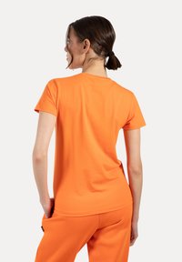 Korte mouwen oranje katoenen T-shirt met een ronde halslijn en een gladde textuur, met een relaxte pasvorm en geen zichtbare patronen of accenten.