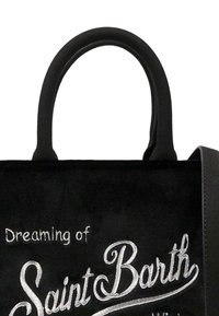 Zwarte suede tote bag met gebogen zwarte handvatten. Voorzien van white geborduurde tekst "Dromen van Saint Barth" in een vloeiende schrift.