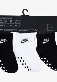 Three pairs of ankle socks: black with white logo, white with black logo. Both have rubber non-slip dots on the bottom for traction.
