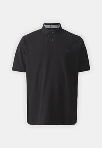 Polo noir en coton, avec un col à deux boutons, des manches courtes et un petit logo sur la poitrine gauche. Intérieur du col à rayures.