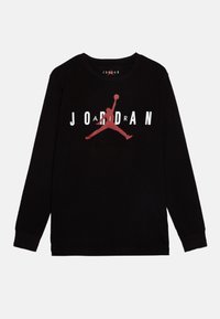 Svart långärmad skjorta av bomull med en stor röd Jumpman-logotyp och "JORDAN" i vita bokstäver ovanför och under logotypen.