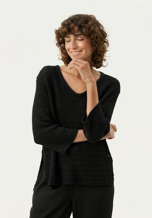 Schwarzer Strickpullover mit lockerer Passform, V-Ausschnitt, Dreiviertelärmeln, strukturiertem Muster und seitlichen Schlitzen. Einfaches und atmungsaktives Material.