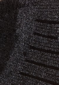 Black knitted fabric with varying textures, featuring a subtle ribbed pattern throughout and smooth sections, creating a dimensional look.