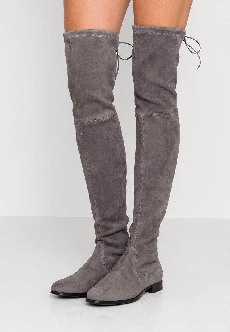 Botas de gamuza gris hasta la rodilla con suela plana, que presentan un diseño holgado y detalles de lazo en la parte superior para un ajuste ajustable.