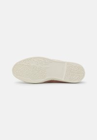 Różowy sneaker z teksturowaną gumową podeszwą, posiadający szczegółowy wzór bieżnika, kontrastującą białą środkową podeszwę oraz gładki materiał wierzchni.