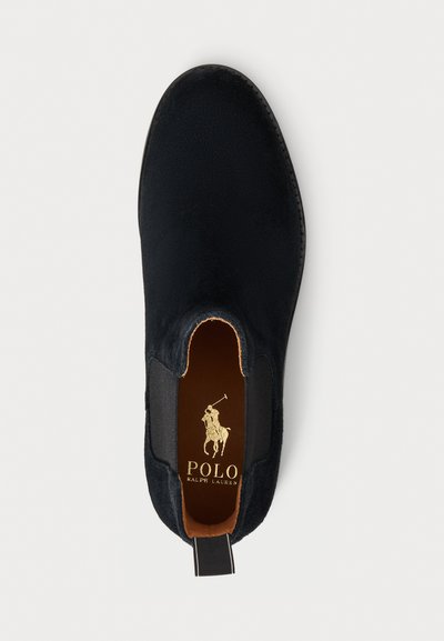 Melnas zamšādas mokasīni ar elastīgām sānu daļām, noapaļotu purngalu un kontrastējošu brūnu iekšpusi. Satur zelta "Polo Ralph Lauren" logo.