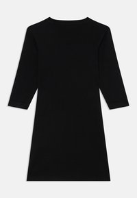 Rochie neagră, cu mânecă lungă și decolteu rotund, cu un croi drept și tiv până la genunchi, realizată dintr-un material neted.