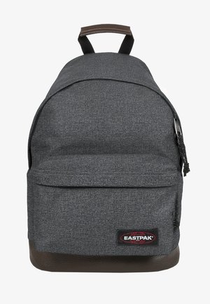 Grijze textielrugzak met een afgeronde vorm, een bruine leren bodem en een voorvak met rits. Voorzien van verstelbare banden en een logopatch.