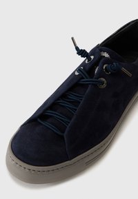 Baskets en suede bleu marine avec un bout arrondi, des lacets élastiques, des accents en métal argenté et une semelle extérieure en caoutchouc gris texturé.