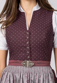 Traditional dress featuring a burgundy bodice with small white floral patterns, silver buttons, and a grey skirt with intricate detailing.