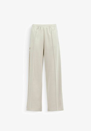 Pantalon beige à jambes droites avec taille élastique et fine rayure à carreaux marron discrète sur le côté gauche.