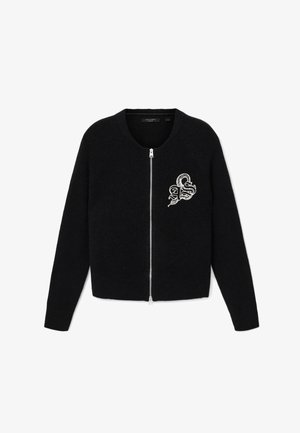 Mustavilla vetoketjullinen neuletakki, joka on valmistettu pehmeästä kankaasta. Siinä on pyöreä kaula-aukko ja brodeerattu logo vasemmalla puolella. Yksinkertainen, lyhennetty malli.