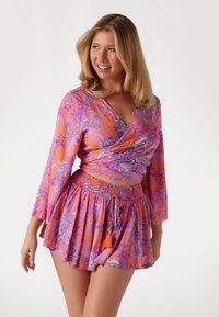 Lila ja appelsinitoonides paisley-mustriga lühike topp pikema varrukaga; sobiv mini-seelik kokku volditud vöökohtade ja tikanditega. 
