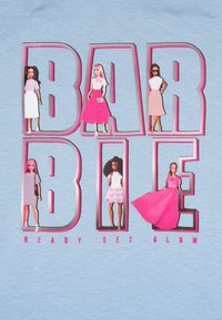 T-shirt azzurro chiaro con grande testo "BARBIE". Bambole stilizzate in vari vestiti, con una combinazione di colori rosa e grigio, arricchite da dettagli e design.