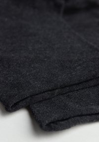 Sort strikket stof med en glat tekstur, der har foldede manchetter. Designet er enkelt og monochromt, med subtile variationer i trådene.