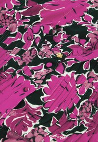 Floral blouse with a pink, black, and white pattern. Features pleating and a gold button detail. Made from lightweight fabric.