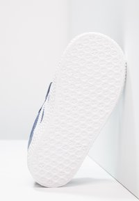 White rubber sole with a textured star pattern. Upper features dark blue fabric and white accents. Side view against a light background.
