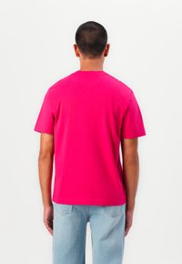 Kortærmet t-shirt med rund hals i lys pink bomuld. Simpelt design med lige kant og uden synlige logoer eller mønstre.