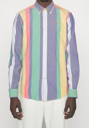 Overhemd met lange mouwen met knopen en verticale strepen in pastel paars, groen, geel, roze en wit, gedragen met een witte broek.