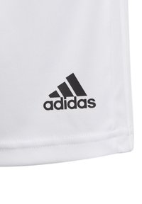 Tecido blanco con el logo negro de Adidas impreso cerca del dobladillo cosido, que muestra tres rayas diagonales y el nombre de la marca.