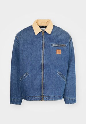 Denimjas met een lichtbruine kraag, voorrits en twee zijzakken. Kenmerkt zich door een klein bruin logopatch op de borst.