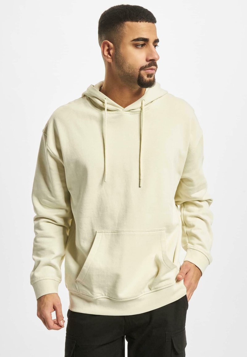 Cremefarvet hættejakke lavet af blødt stof, med en frontlomme i kangaroo-stil, snøre og ribbede manchetter. Casual og komfortabelt design.