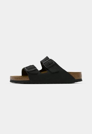 Black sandal with two adjustable buckles, a cork footbed, and a textured, rubber sole. Features a minimalist design and open-toe style.