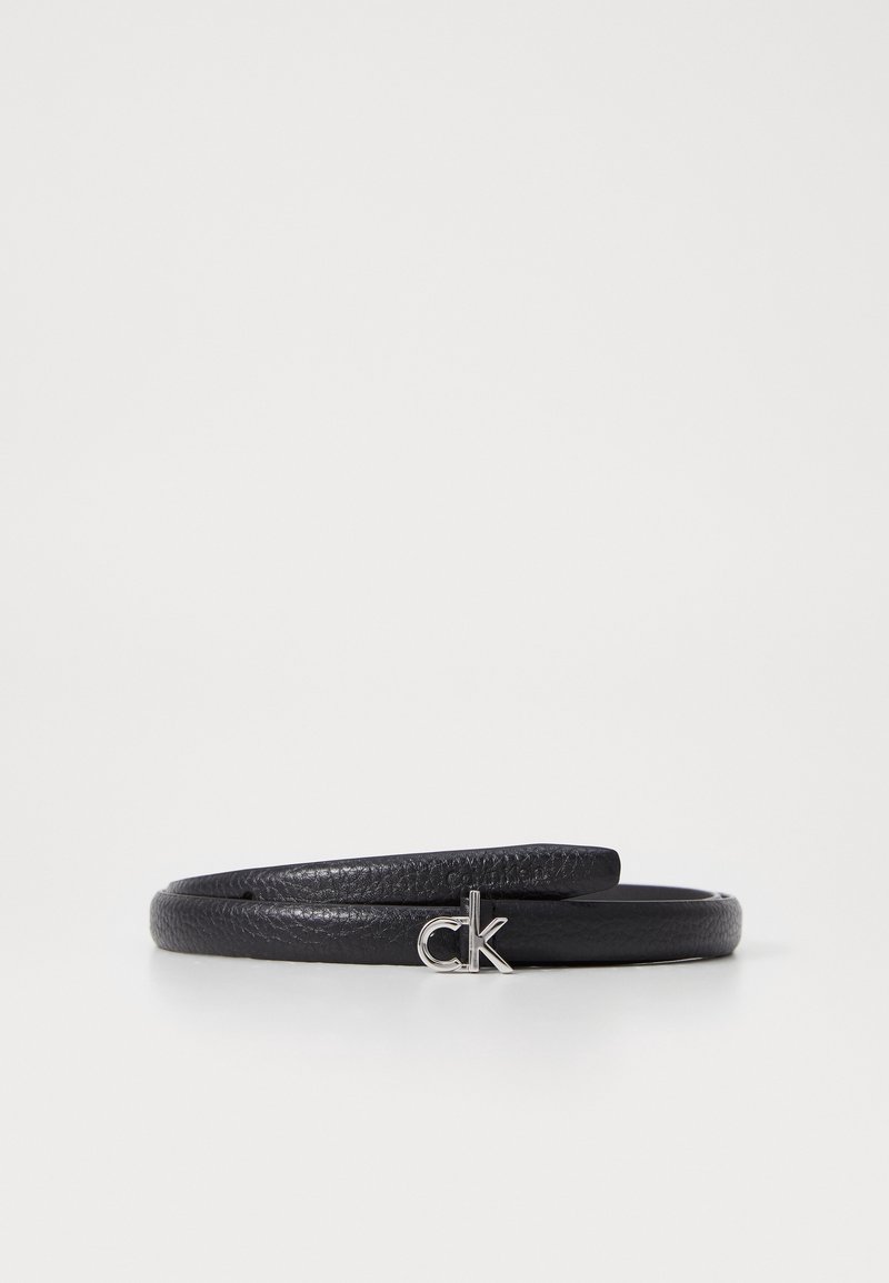 Ceinture en cuir noir texturé enroulée avec une petite boucle logo argentée "ck" sur fond blanc.