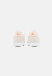 Fehér sneakers bőr bézs sarokkal és hímezett logóval. Jellemzője a sima felsőrész, kerek orr és lapos gumi talp.