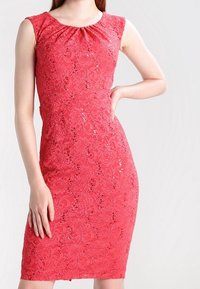 Robe rouge en dentelle avec une silhouette ajustée, des manches courtes papillon et un col froncé. Présente des motifs floraux et des accents de paillettes.