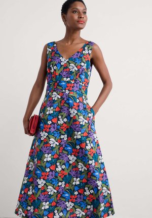 Rochie florală cu decolteu în V, fără mâneci și fustă evazată. Confectionată dintr-un material cu un model vibrant de flori roșii, albastre, mov și albe.