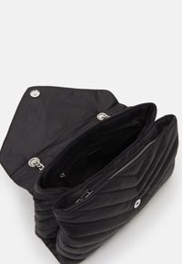 Černá prošívaná kabelka s měkkou strukturou, stříbrnými kovovými doplňky a širokým otevíráním. Má dvě hlavní přihrádky a vnitřní kapsu na zip.