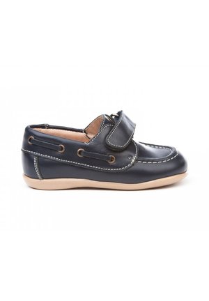 Mocasin de niño en cuero azul marino con suela marrón, correa de velcro, costuras blancas y diseño de zapato de barco de fácil puesta.