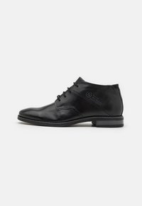 Zapato de vestir de cuero negro con un diseño elegante, puntera redonda y cierre de cordones. Presenta una textura suave y un tacón bajo apilado.