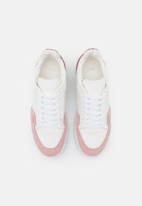 Białe i różowe sneakersy z gładką skórzaną cholewką i zamszowymi akcentami. Posiadają puszystą wyściółkę, okrągłe sznurowadła i perforowaną strefę palców.