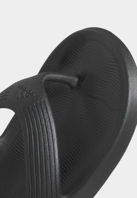 Svart gummisandal med en strukturerad sula, en tårem och räfflade detaljer på remmen för ökat grepp och komfort.