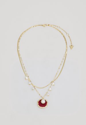 Collier à double chaîne en or avec de petites perles blanches ; la chaîne inférieure porte un pendentif rouge festonné avec une perle centrale.