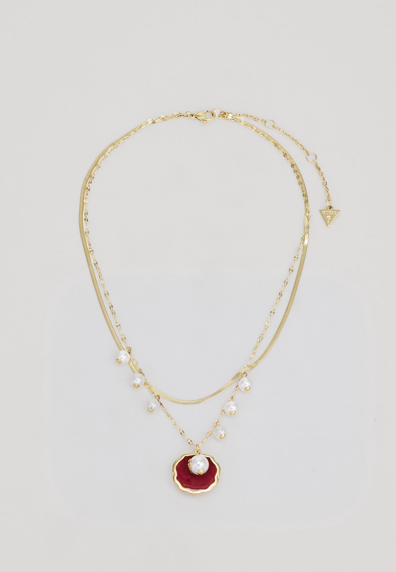 Collier à double chaîne en or avec de petites perles blanches ; la chaîne inférieure porte un pendentif rouge festonné avec une perle centrale.