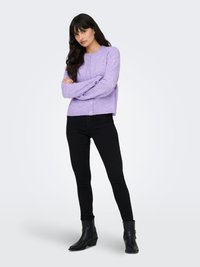 Lavendelfarget strikket cardigan med lange ermer og knapper foran, kombinert med svarte skinny jeans og svarte ankelstøvletter med hæl.