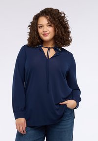 Blusa blu navy in tessuto leggero con maniche lunghe, scollo a goccia, coulisse e dettaglio collo decorato.