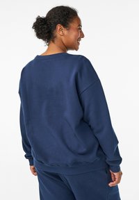Sudadera de algodón azul marino con un corte relajado, escote ancho y puños de canalé. Presenta una textura suave y sin patrones ni acentos visibles.