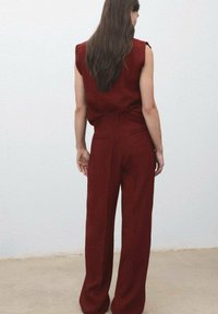 Bordó dvoudílný outfit se bezramenným topem a kalhotami s vysokým pasem a širokými nohavicemi. Hladká textura s minimalistickým designem.