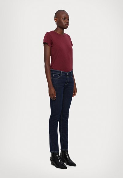 Maroon short-sleeve t-shirt, dark blue skinny jeans, and black ankle boots. Smooth fabric and fitted design with subtle detailing on jeans.