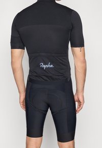 Maillot et cuissard de cyclisme noirs à design texturé et ajusté. Arborent le logo Rapha bleu clair dans le dos, manches courtes et siège rembourré.