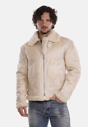 Giacca in shearling beige chiaro con zip frontale, colletto ampio e due tasche anteriori. Caratterizzata da una texture morbida e una vestibilità strutturata.