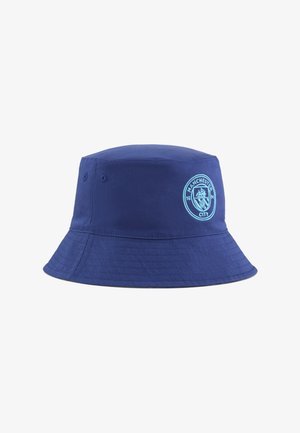 Námornícky modrý kyblíkový klobúk vyrobený z odolnej látky, s pevnou korunou, širokým okrajom a vyšitým logom Manchester City na prednej strane.