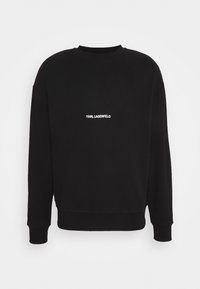 Czarna bluza z okrągłym dekoltem, ściągaczami na rękawach i u dołu. Na piersi biały napis "KARL LAGERFELD". Miękka tekstura materiału.