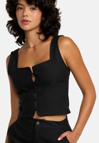Zwarte crop top met een vierkante halslijn, knoopsluiting en mouwloos ontwerp. Gemaakt van textuurstof en voorzien van minimalistische accenten.