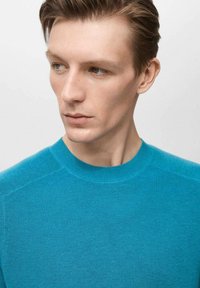 Tyrkysový pletený svetr s kulatým výstřihem a žebrovanou texturou, se hladkými rameny a přiléhavými rukávy. Jednoduchý design, bez vzorů.